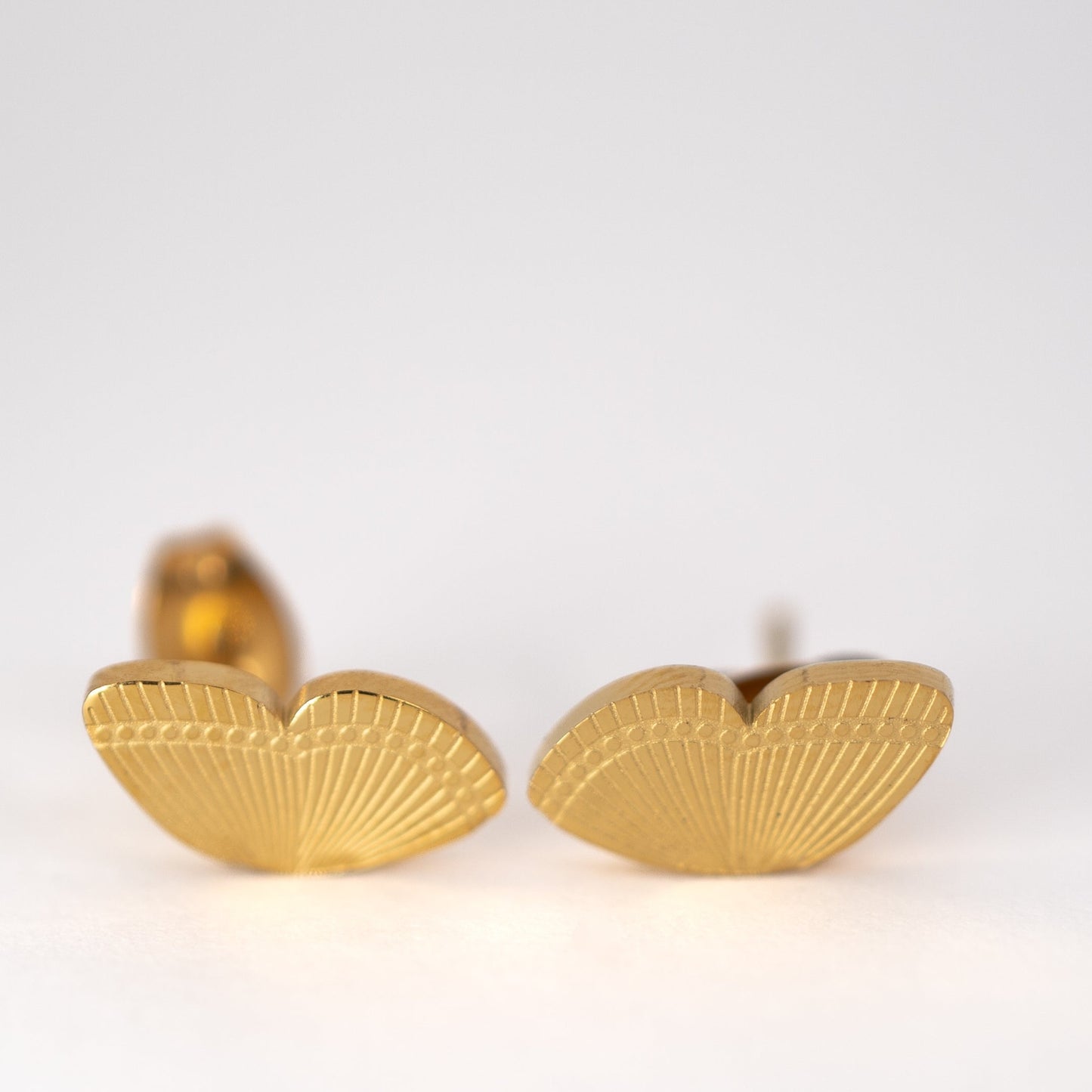Lula Sea Jewellery, Monarch butterfly wing stud earrings, two single wing stud earrings engraved with the wing pattern gold plated, pictured on flat surface front view