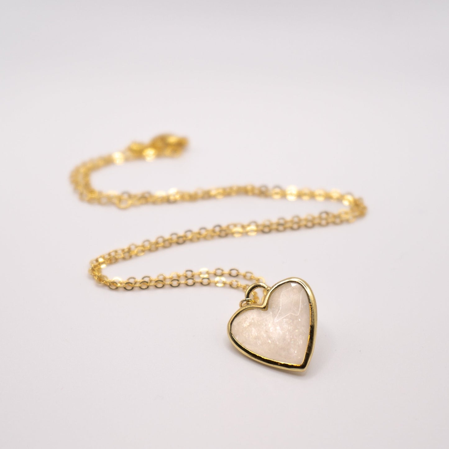 Lula sea Jewellery New Zealand moonstone heart pendant necklace, made from 18k gold and natural facet cut gem stone, vermeil, pictured laying on flat surface